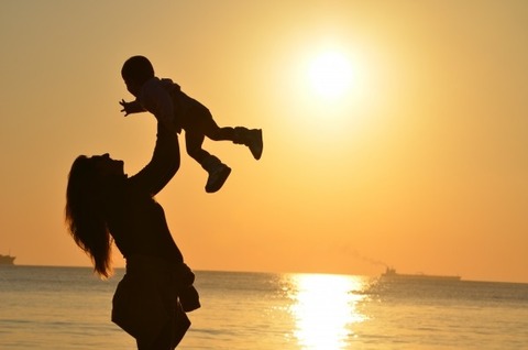 silhouette-of-mother-holding-her-baby-aloft-at-seaside