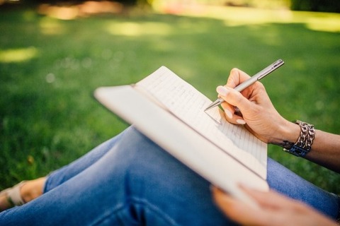 woman-writing-in-netbook-sitting-in-park