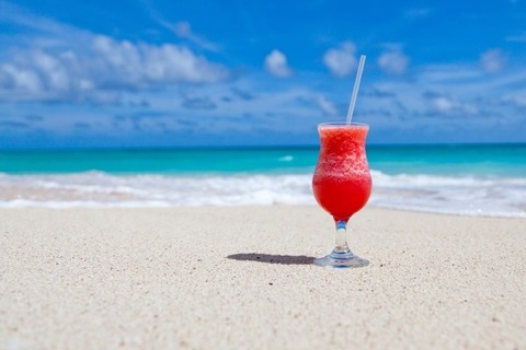 close-up-of-cocktail-drink-with-drinking-straw-on-beach